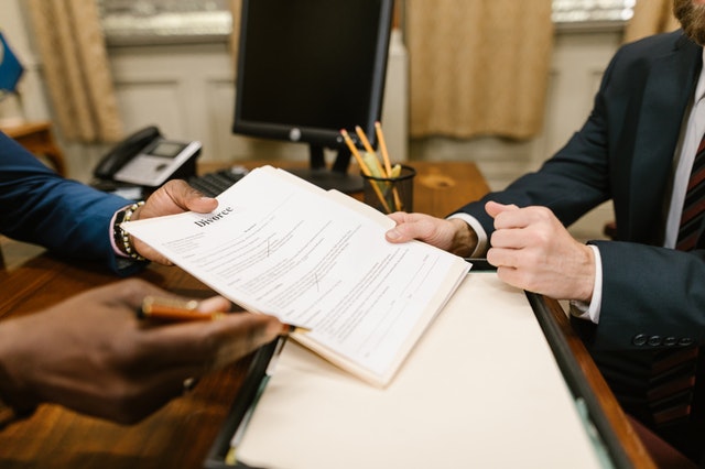 A person holding a pen and paper and giving it to another person to sign.