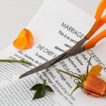 A pair of scissors cutting a marriage certificate and an orange rose