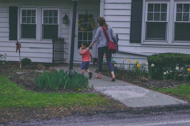 A woman entering a house with her son