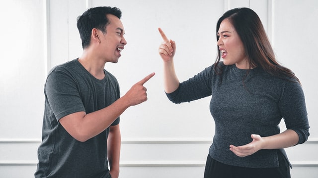 A man in a gray t-shirt arguing with a woman in a grey sweater.