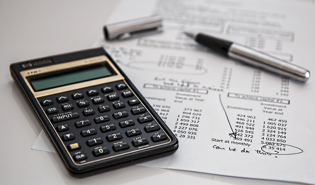 A paper with budget calculations, a pen, and a calculator.