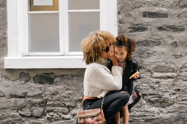 A mother whispering something to her daughter