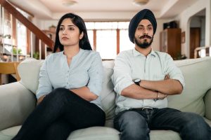 Couple sitting on a couch next to each other, visibly upset signs of divorce