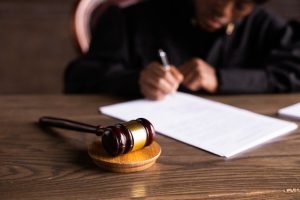 A gavel on a table with a judge in the background.