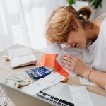 Stressed woman sitting at a desk with her head on the pile of receipts and cashe to symbolize navigating the divorce process on a tight budget.