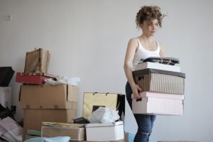 Women decluttering after a divorce and carrying a pile of boxes away from clutter. 