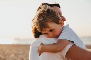 A mother hugging child outdoors for mental health. 