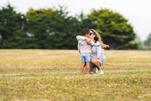 A mother hugging a child outdoors.