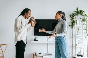 Couple standing in front of a TV in their living room and arguing