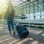 Woman carrying a suitcase and walking towards the airport