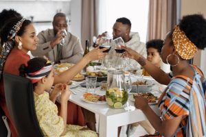 A family sitting at the table, eating and drinking vine.