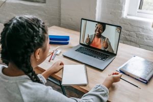 A young girl is engaging in a video call with a smiling woman, which is indicative of long-distance co-parenting arrangements.