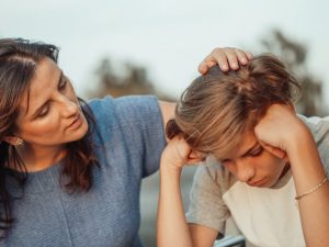 Woman consoling a distressed child outdoors, representing the emotional support vital in co-parenting relationships.